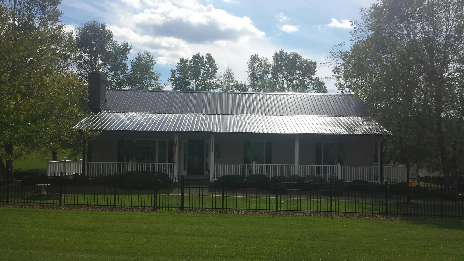 Gray metal roof on a brick ranch with a full width front porch — Gutter Guard Installation work by our crew in Perry